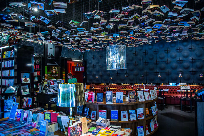 Interior of a grandiose bookstore with books hanging from the ceiling and cozy seating in a magical atmosphere.